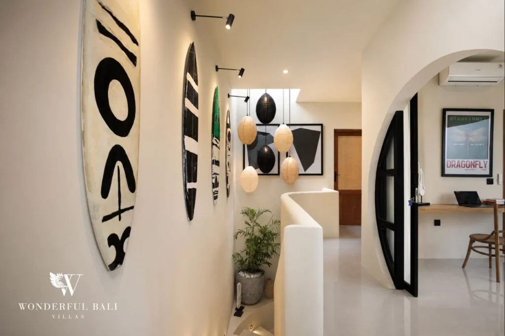 An upstairs hallway with surfboard art and a built-in desk work nook at a 3-bedroom villa in Pererenan, Bali
