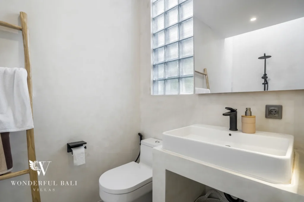 Bathroom with floating stone vanity and glass-block window at a 3-bedroom villa in Pererenan, Bali