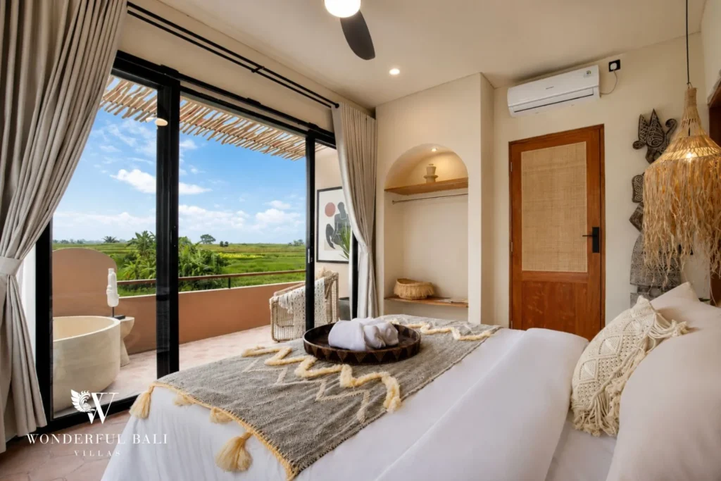 A queen bedroom with a private balcony bathtub and rice-field views through sliding doors at a 3-bedroom villa in Pererenan, Bali