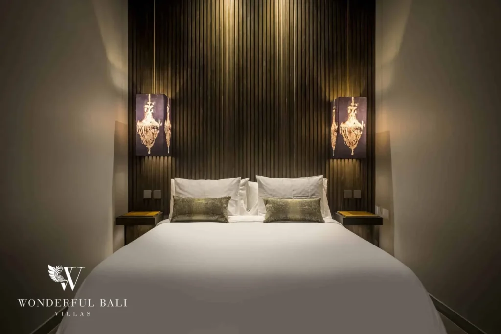 A softly lit bedroom with a white bed centred against a slatted wood feature wall flanked by illuminated art panels at a 3-bedroom villa in Pererenan, Bali