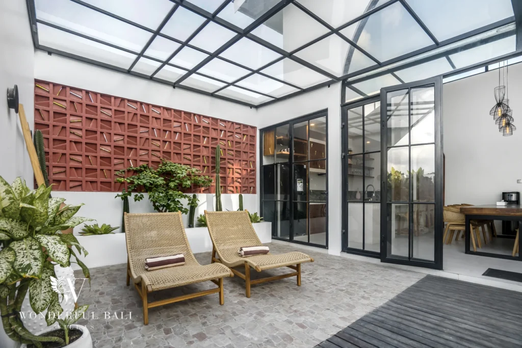 Covered terrace with rattan loungers and glass roof at a 3-bedroom villa in Pererenan, Bali
