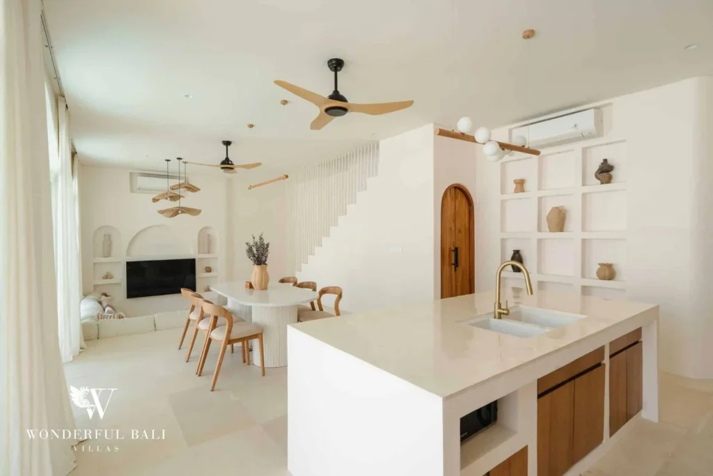The kitchen island with a gold tap opening onto a round dining table and lounge beyond, at a 2-bedroom villa in Bingin, Uluwatu, Bali