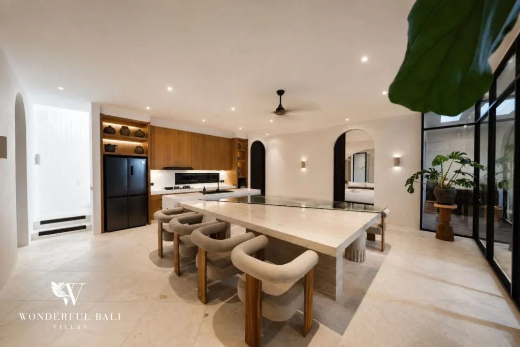 Travertine dining table seating eight beside the teak kitchen in a 4-bedroom villa in Canggu Bali