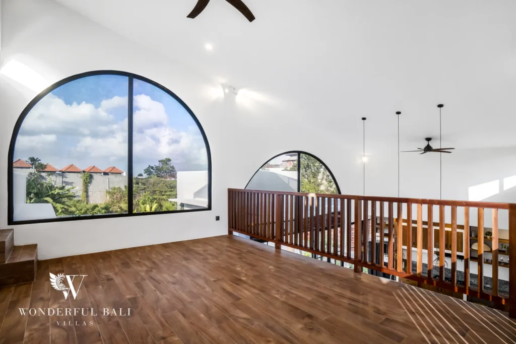 Mezzanine loft with arched windows and ceiling fan at a 3-bedroom villa in Pererenan, Bali