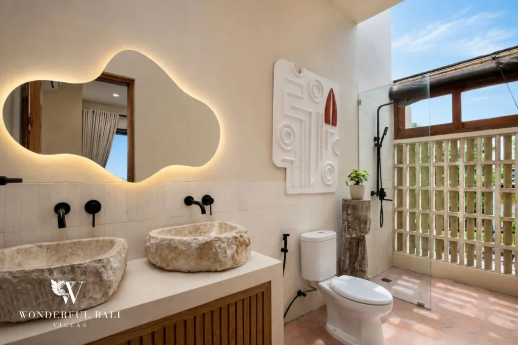 An en-suite bathroom with dual stone basins, a backlit mirror and glass-block shower at a 3-bedroom villa in Pererenan, Bali