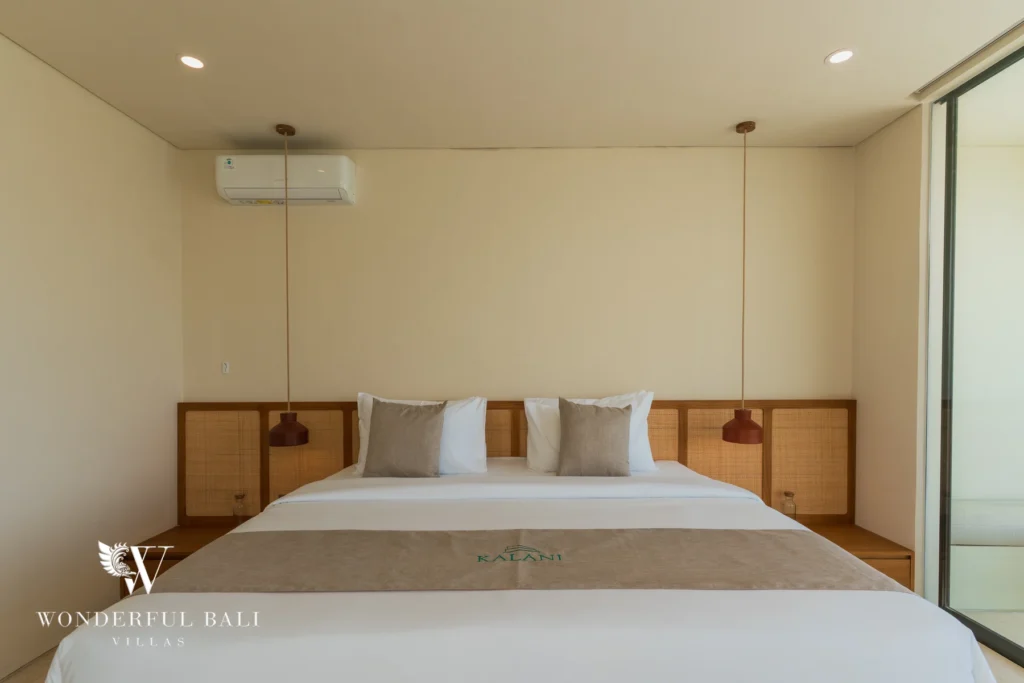 A bedroom with a woven rattan headboard, matching bedside cabinets and rattan pendant lights at a 3-bedroom villa in Bingin, Uluwatu, Bali