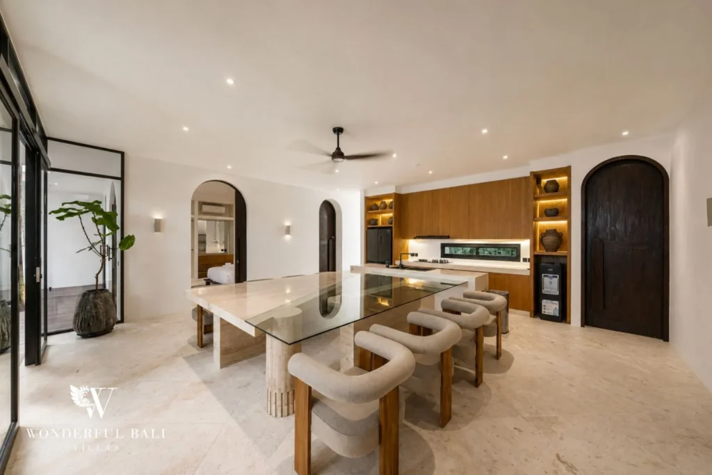 Dining table and teak kitchen with arched doorways in a 4-bedroom villa in Canggu Bali