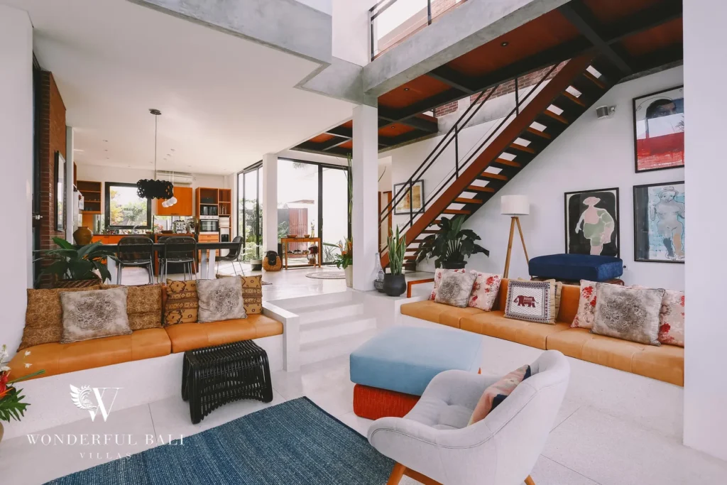 An open-plan living and dining space with leather bench seating, a floating staircase and views through to the kitchen at a 4-bedroom villa in Batu Bolong, Canggu, Bali