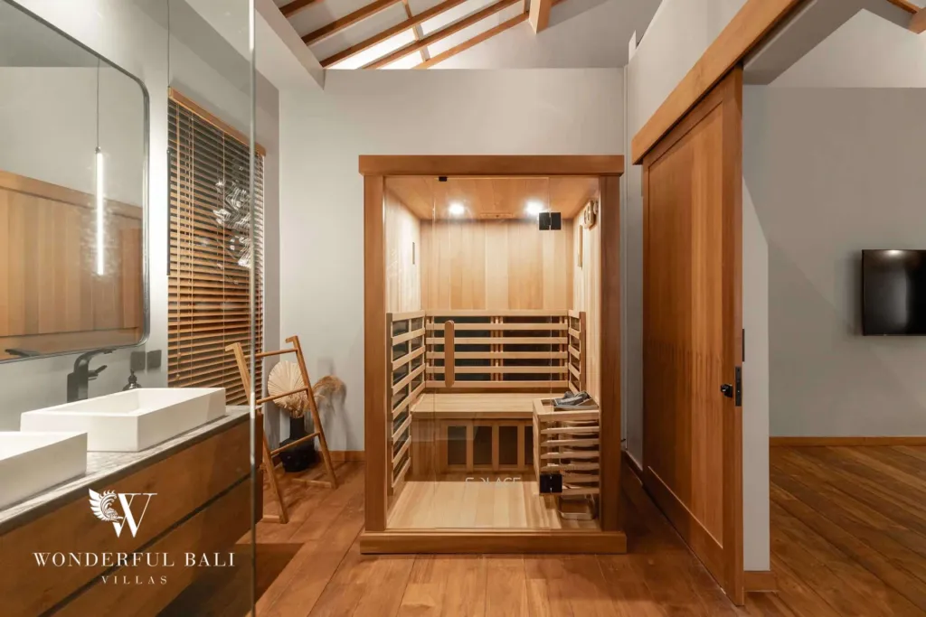 2BR villa for rent in Pererenan — sauna, a wood-lined infrared sauna with slatted benches beside a timber vanity and mirror under a beamed ceiling at a 2-bedroom villa