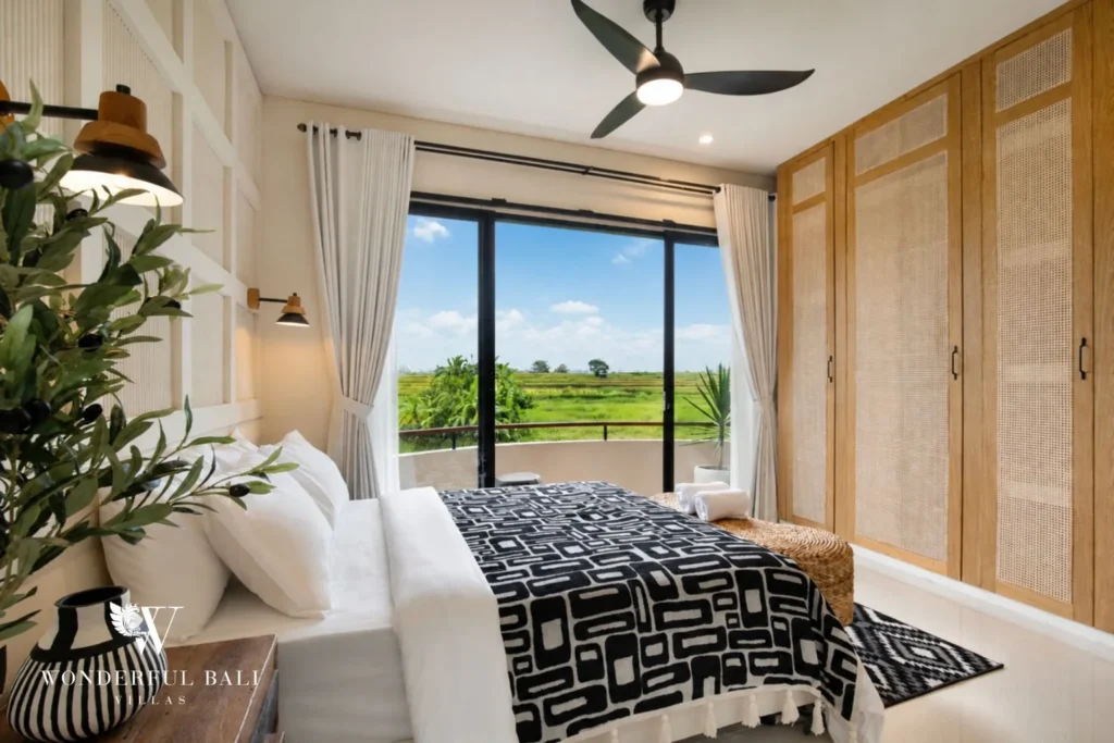 A queen bedroom with rattan wardrobes and sliding doors framing rice-field views at a 3-bedroom villa in Pererenan, Bali