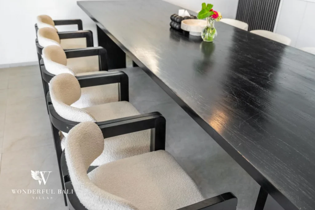 Close-up of the black dining table and cream boucle chairs with a floral centrepiece at a 5-bedroom villa in Pererenan, Bali