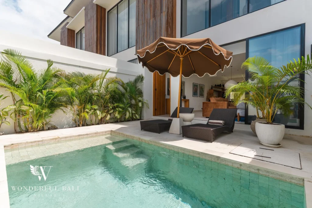 A private pool bordered by tropical plants with sun loungers under a parasol beside the villa at a 2-bedroom villa in Canggu, Bali