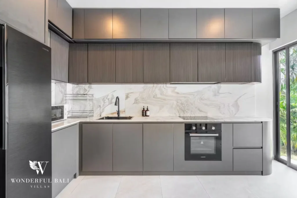 Fully equipped modern kitchen with grey cabinetry, marble backsplash and built-in oven at a 5-bedroom villa in Pererenan, Bali