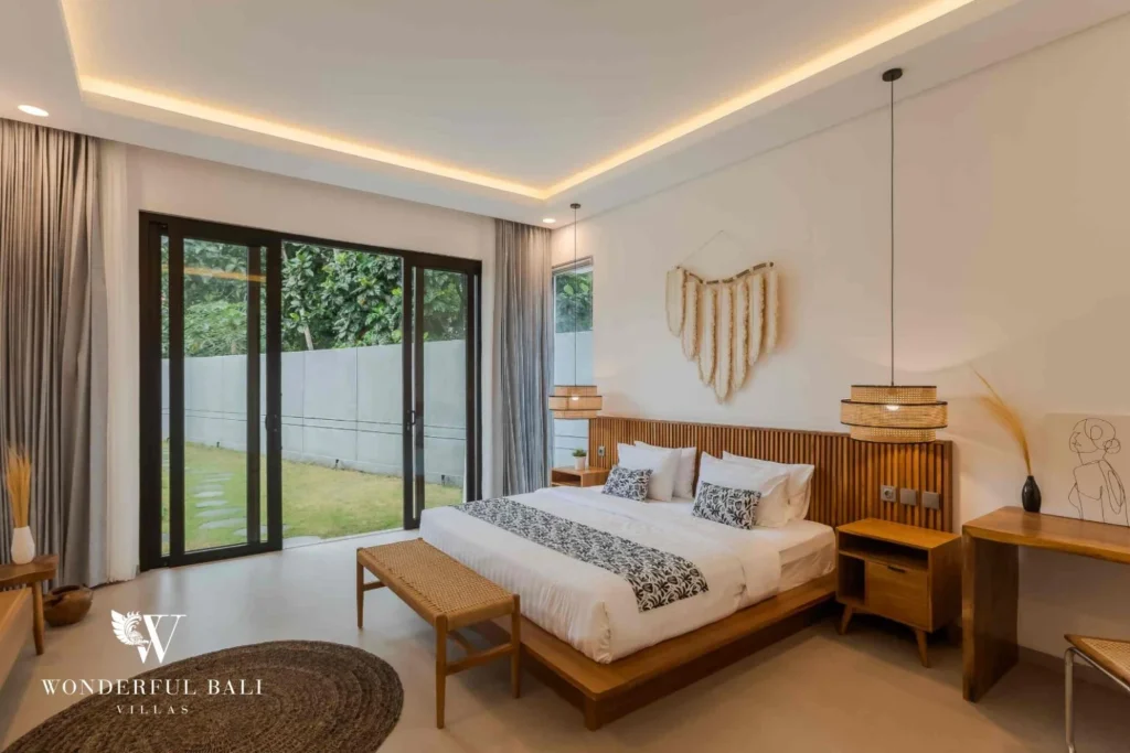 A king bedroom with timber-slatted headboard, sliding doors to the garden and woven wall hanging at a 4-bedroom villa in Pererenan, Bali