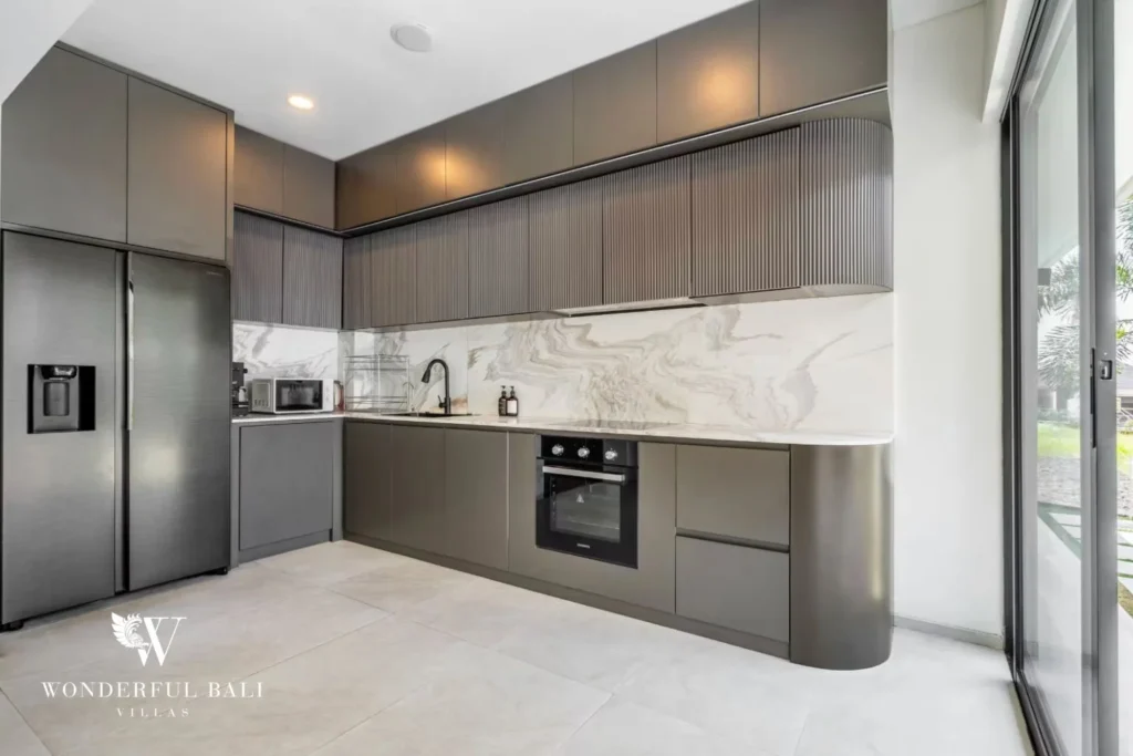 Wider view of the grey modern kitchen with stainless fridge and marble worktops at a 5-bedroom villa in Pererenan, Bali