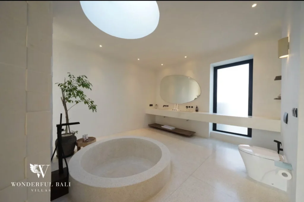 Master bathroom with round terrazzo tub under an oval skylight in a 4-bedroom villa in Canggu Bali