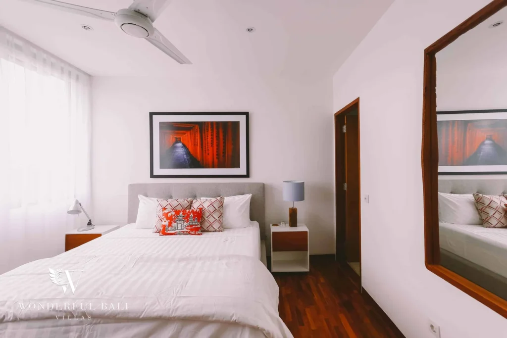 A bedroom with a grey headboard, red torii-gate artwork above the bed and a large timber-framed mirror at a 4-bedroom villa in Batu Bolong, Canggu, Bali