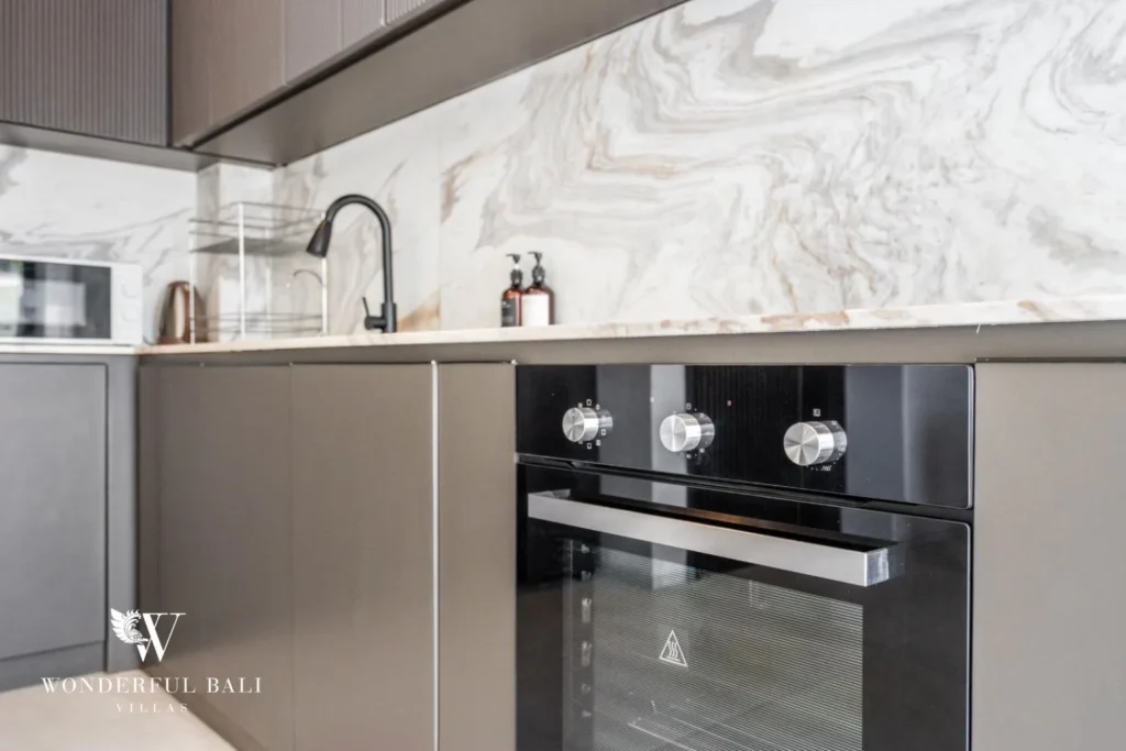 Detail of the kitchen sink, black tap and built-in oven against a marble backsplash at a 5-bedroom villa in Pererenan, Bali