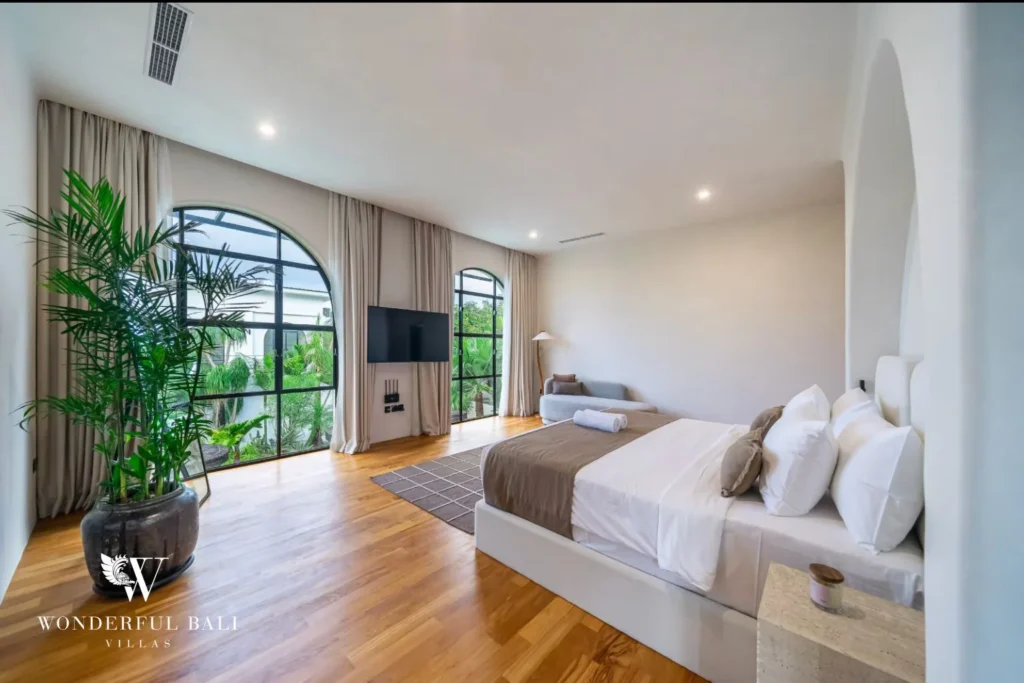 Bedroom with timber floors and tall arched windows in a 4-bedroom villa in Canggu Bali