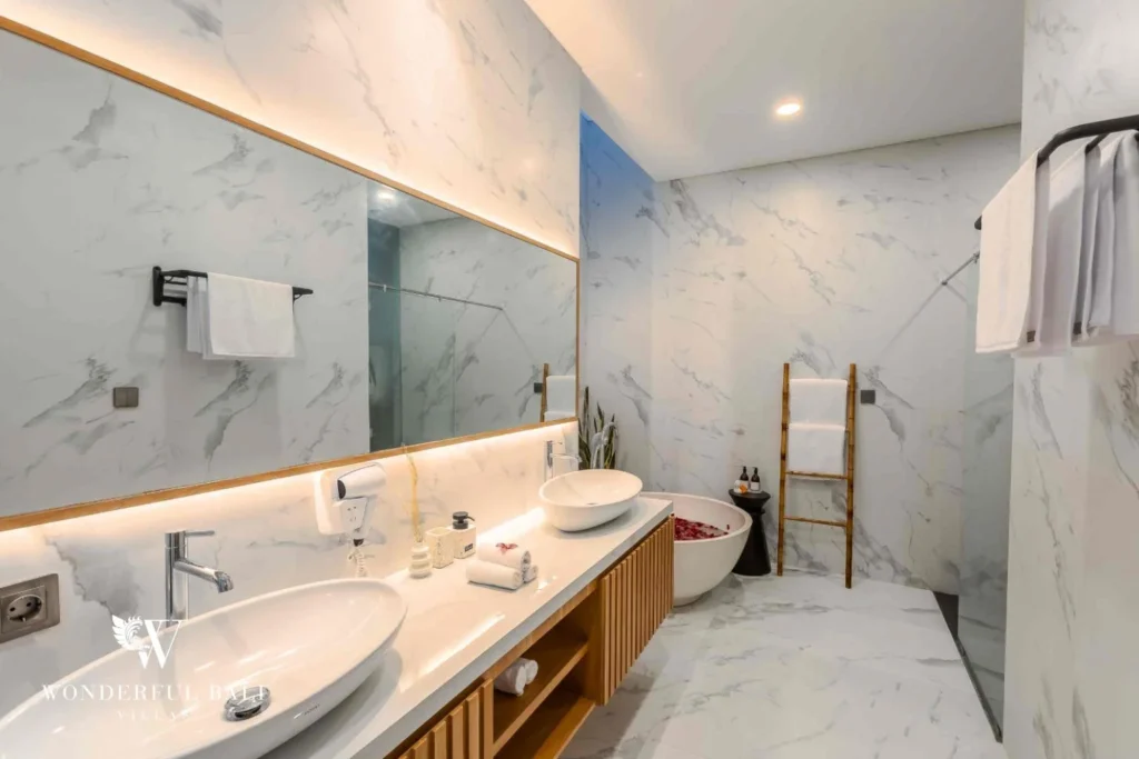 A marble ensuite bathroom with double vessel sinks, backlit mirror and a stone soaking tub at a 4-bedroom villa in Pererenan, Bali