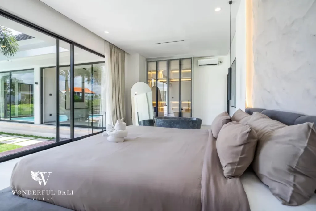 Spacious main suite with a king bed, freestanding stone bathtub and glass doors to the pool at a 5-bedroom villa in Pererenan, Bali