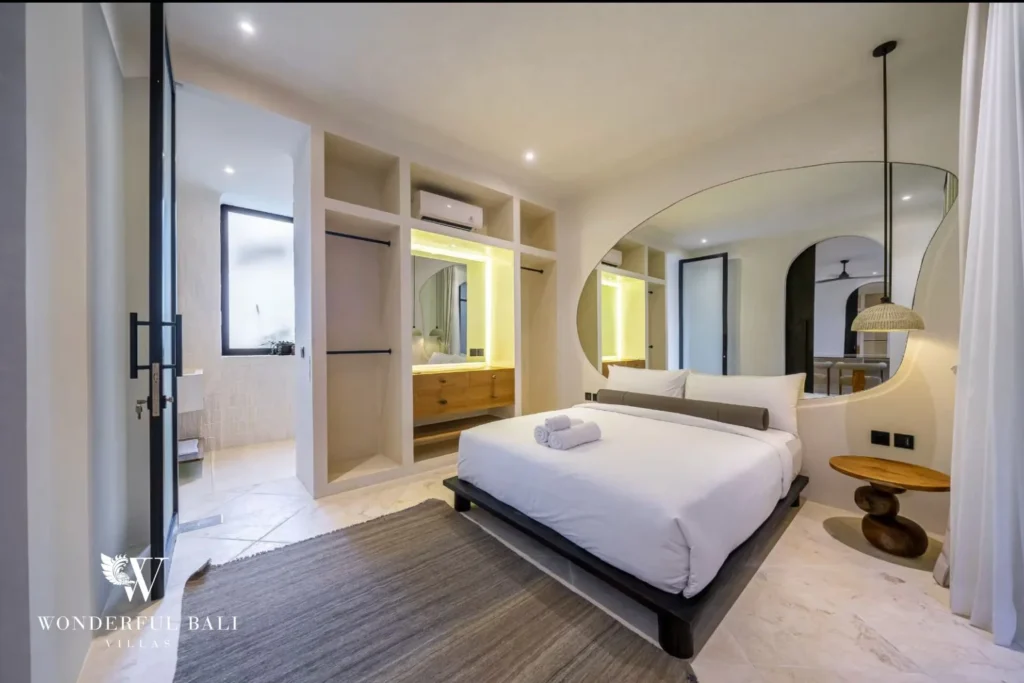 Bedroom with organic-shaped mirror open wardrobe and en-suite in a 4-bedroom villa in Canggu Bali