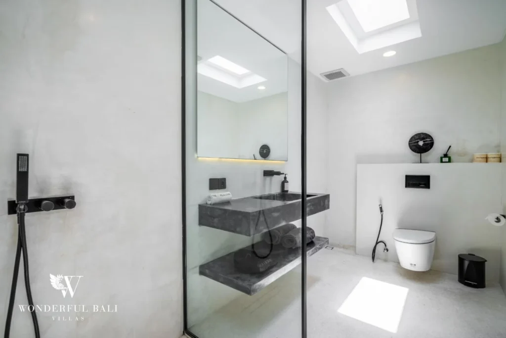 Minimalist en-suite bathroom with a stone vanity, walk-in shower and skylight at a 5-bedroom villa in Pererenan, Bali