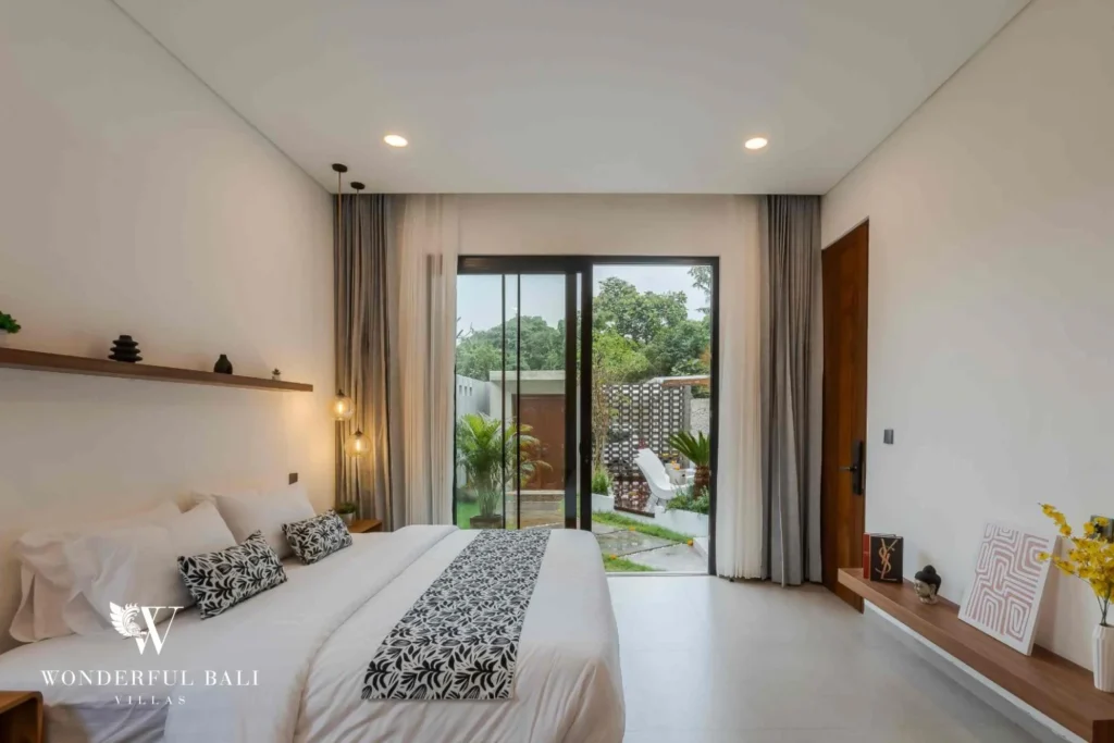 A serene king bedroom with sliding glass doors opening onto the pool garden at a 4-bedroom villa in Pererenan, Bali