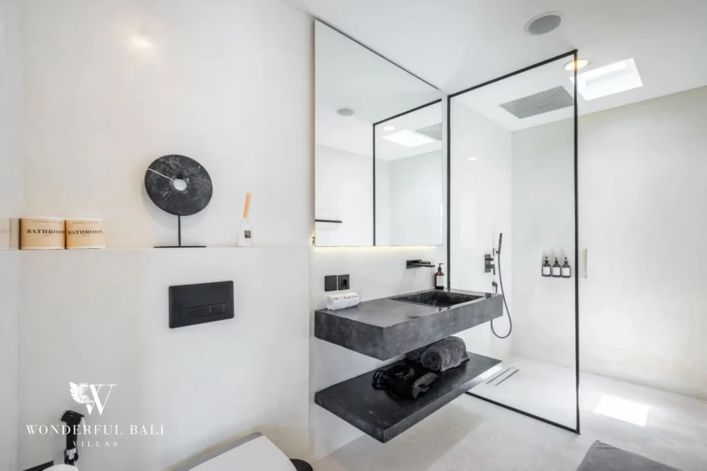 En-suite bathroom with a dark stone floating vanity, large mirror and walk-in shower at a 5-bedroom villa in Pererenan, Bali