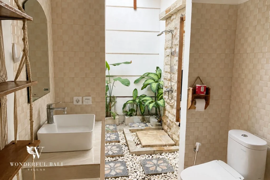 Semi-outdoor bathroom with patterned stone tiles and plants at a villa in Batu Bolong, Canggu