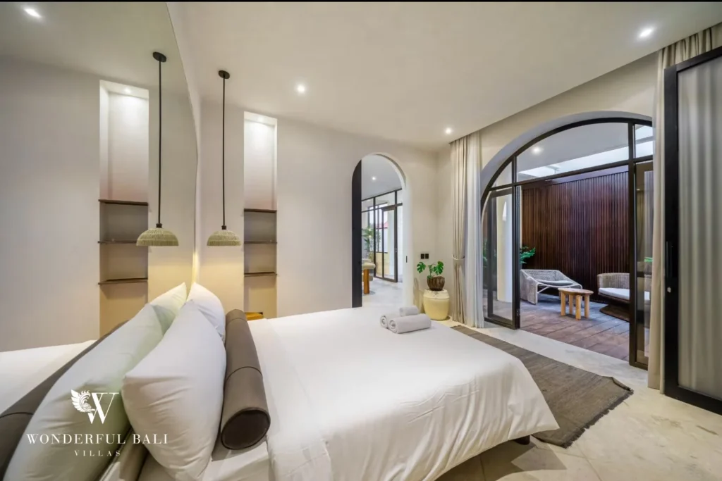 Bedroom with arched door opening to a private deck in a 4-bedroom villa in Canggu Bali