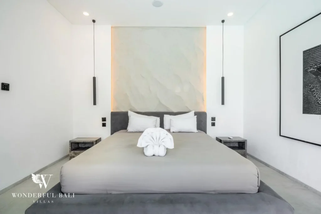 Minimalist king bedroom with a textured headboard panel, pendant lights and framed art at a 5-bedroom villa in Pererenan, Bali