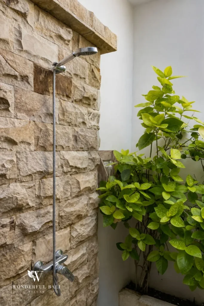 Outdoor stone shower with tropical plants at a villa in Batu Bolong, Canggu