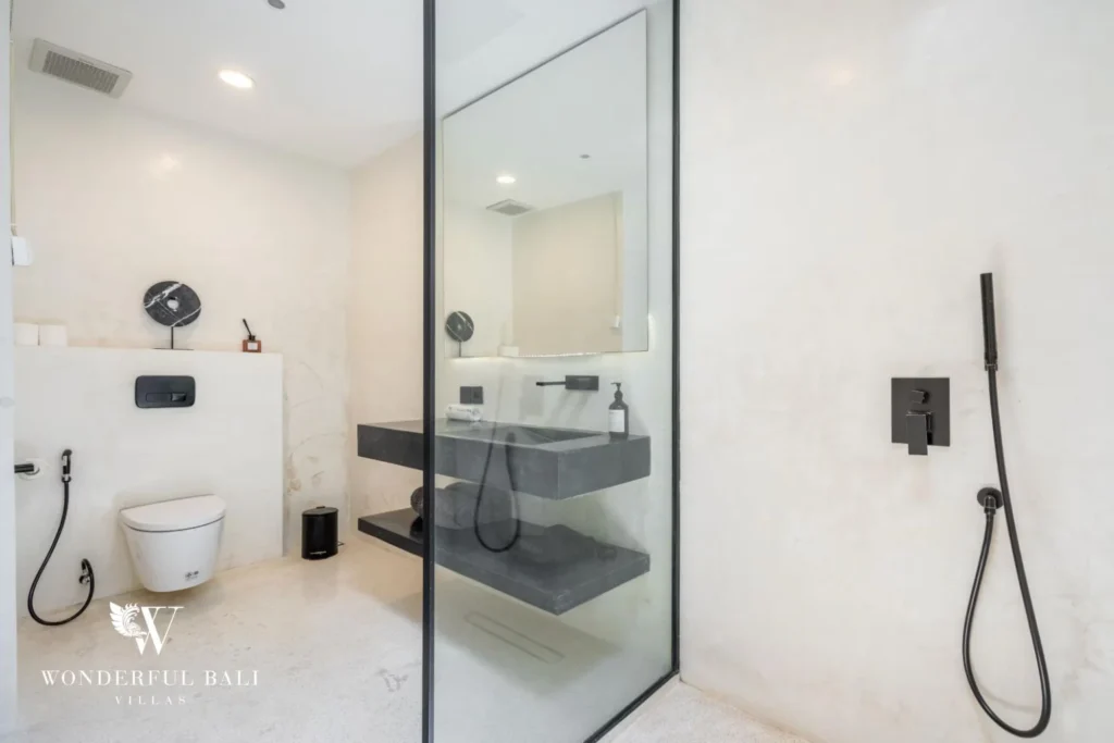 En-suite bathroom with a floating stone vanity, wall-hung toilet and glass-partitioned shower at a 5-bedroom villa in Pererenan, Bali