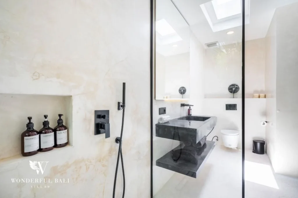 En-suite bathroom in warm travertine tones with a stone vanity, walk-in shower and skylight at a 5-bedroom villa in Pererenan, Bali