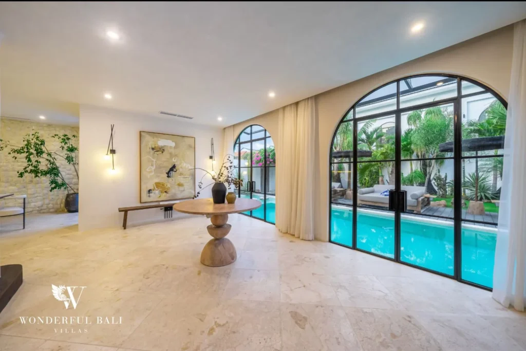 Entrance hall with travertine floors and arched windows onto the pool in a 4-bedroom villa in Canggu Bali