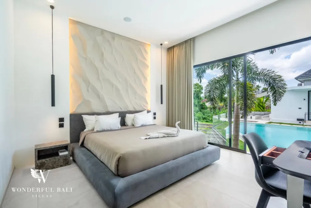 King bedroom with a textured headboard and desk overlooking the private pool at a 5-bedroom villa in Pererenan, Bali