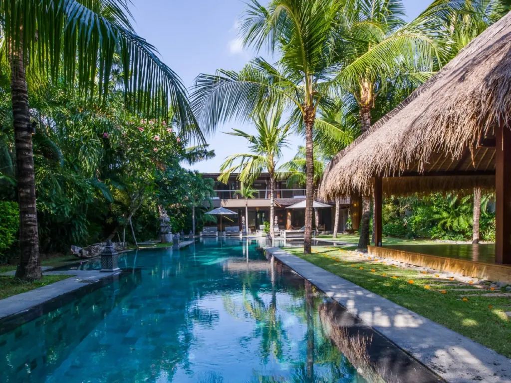 Villa Yoga's pool seen from the lawn, with the thatched yoga bale beyond