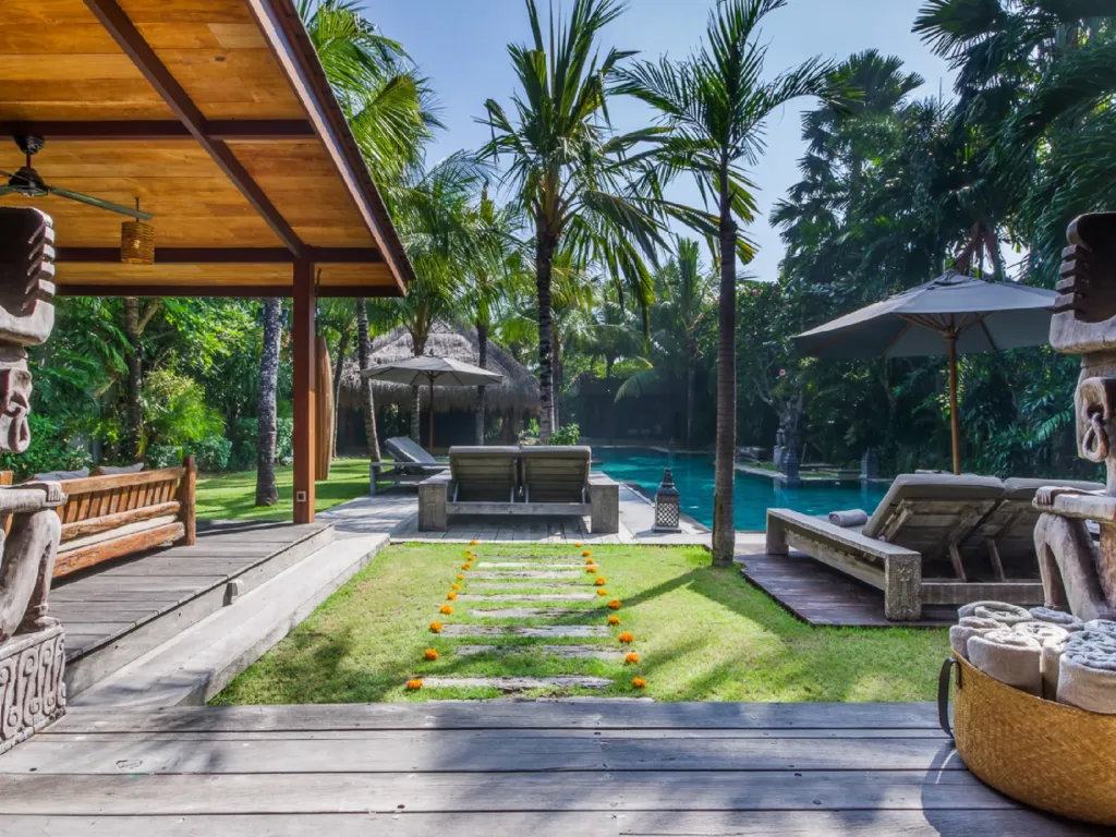 The lawn and pool terrace at Villa Yoga, with loungers under the palms