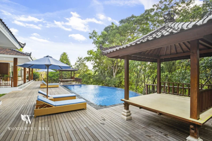 Infinity pool and carved timber bale over a wooded valley at a 3-bedroom villa in Kaba-Kaba Bali