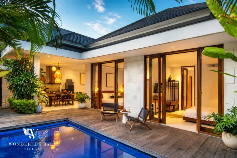 2BR villa for rent in Bumbak, Umalas — pool, timber deck with the living pavilion and bedroom lit at dusk at a 2-bedroom villa