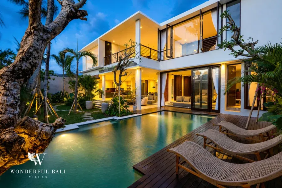4BR villa for rent in Seminyak — pool, pool and villa lit at dusk with sun loungers on the deck