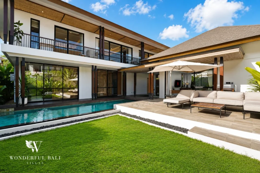 Two-storey villa with pitched shingle roof above a lap pool and lawn at a 3-bedroom villa in Jimbaran Bali