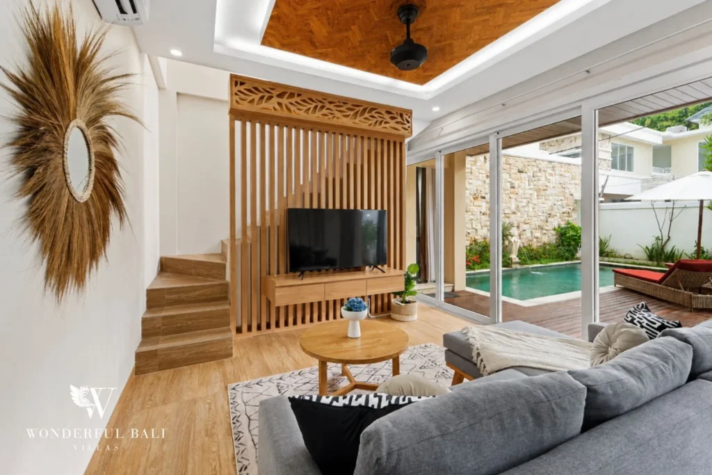 Living room with carved timber screen opening to the pool in a 3-bedroom villa in Tumbak Bayuh Bali
