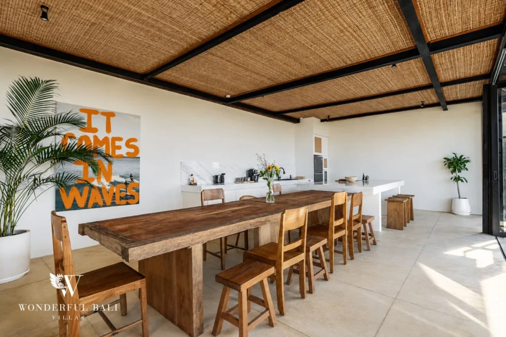 Reclaimed teak table seating ten beside a white marble island in a 5-bedroom villa in Uluwatu Bali