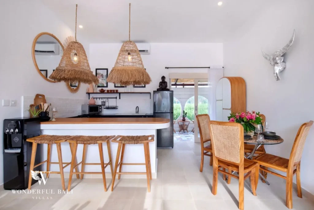 Curved white kitchen island with teak top and raffia pendants in a 3-bedroom villa in Umalas Bali