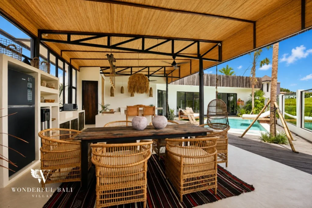 Rattan dining table under a bamboo roof beside the pool at a 3-bedroom villa in Umalas Bali