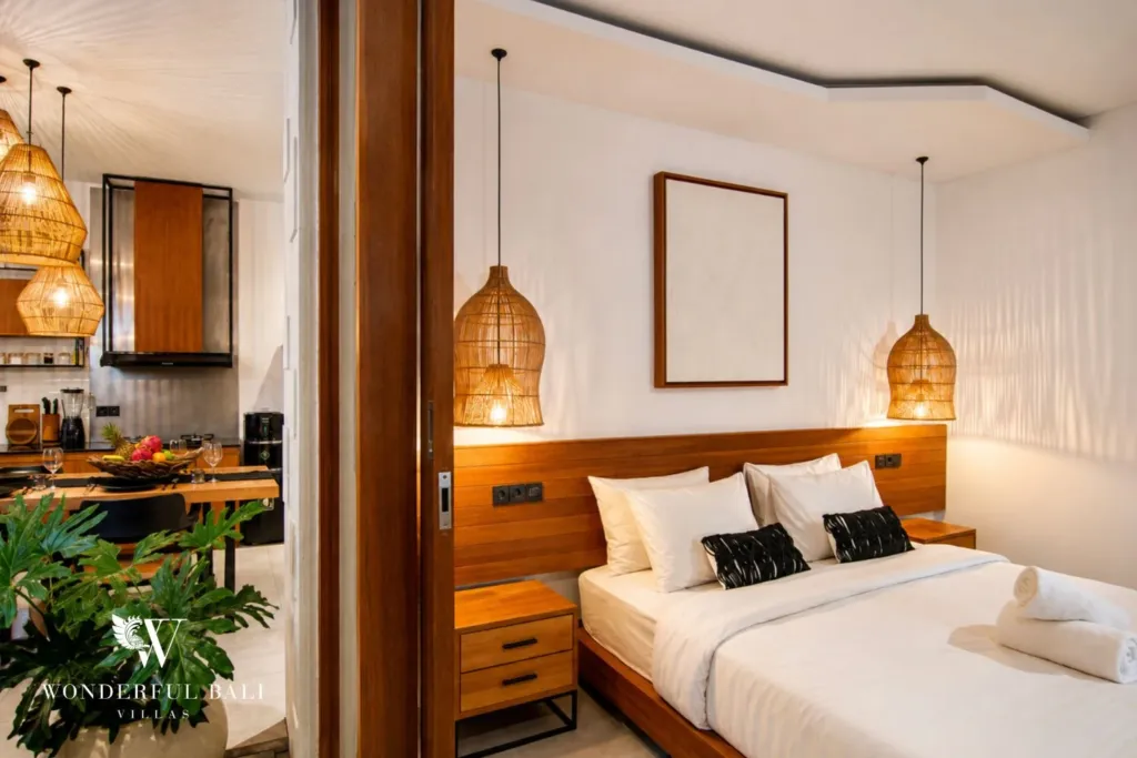 2BR villa for rent in Bumbak, Umalas — bedroom, a king bed and timber headboard seen through sliding doors from the kitchen