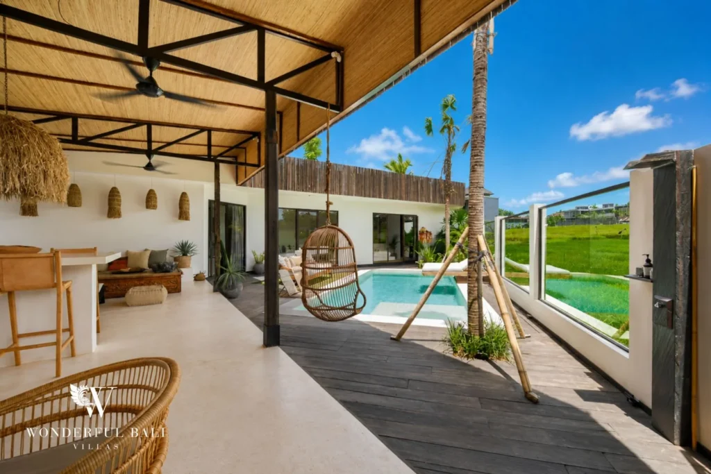 Open-air living pavilion with a hanging rattan chair over the pool deck in Umalas Bali