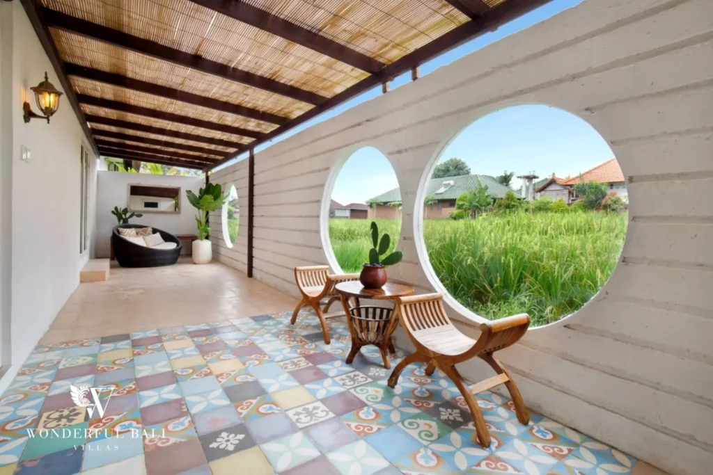 Covered terrace with circular openings onto rice paddy and encaustic tile floor at a 3-bedroom villa in Umalas Bali